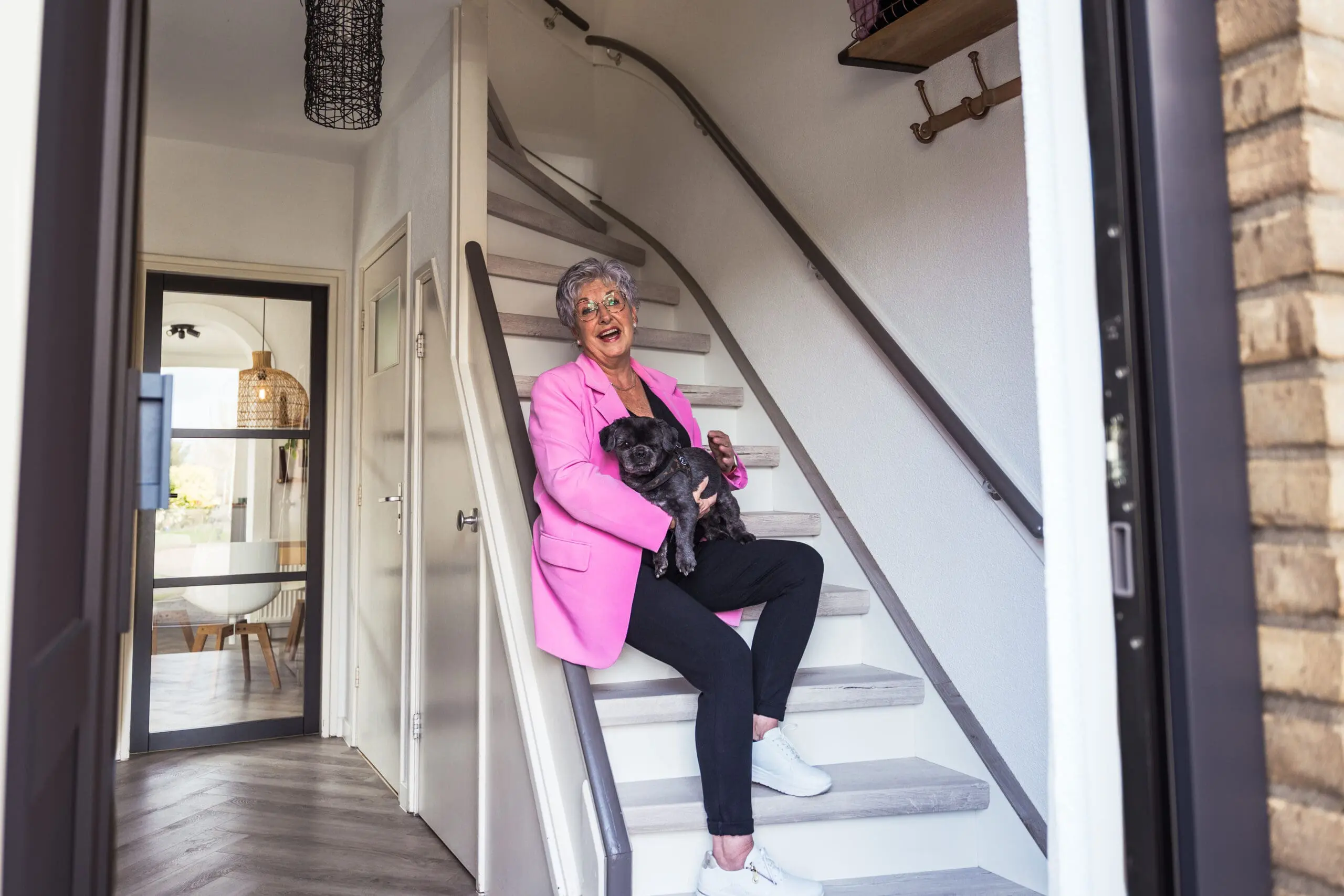 Vrouw zit samen met haar hondje op de pas gerenoveerde trap te lachen.