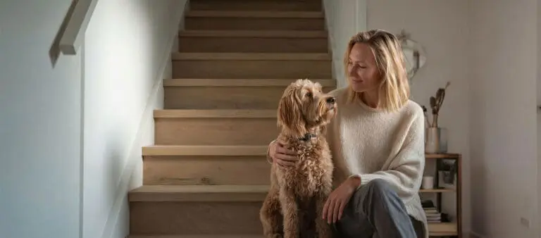vrouw die samen met haar hond voor een pas gerenoveerde trap zit