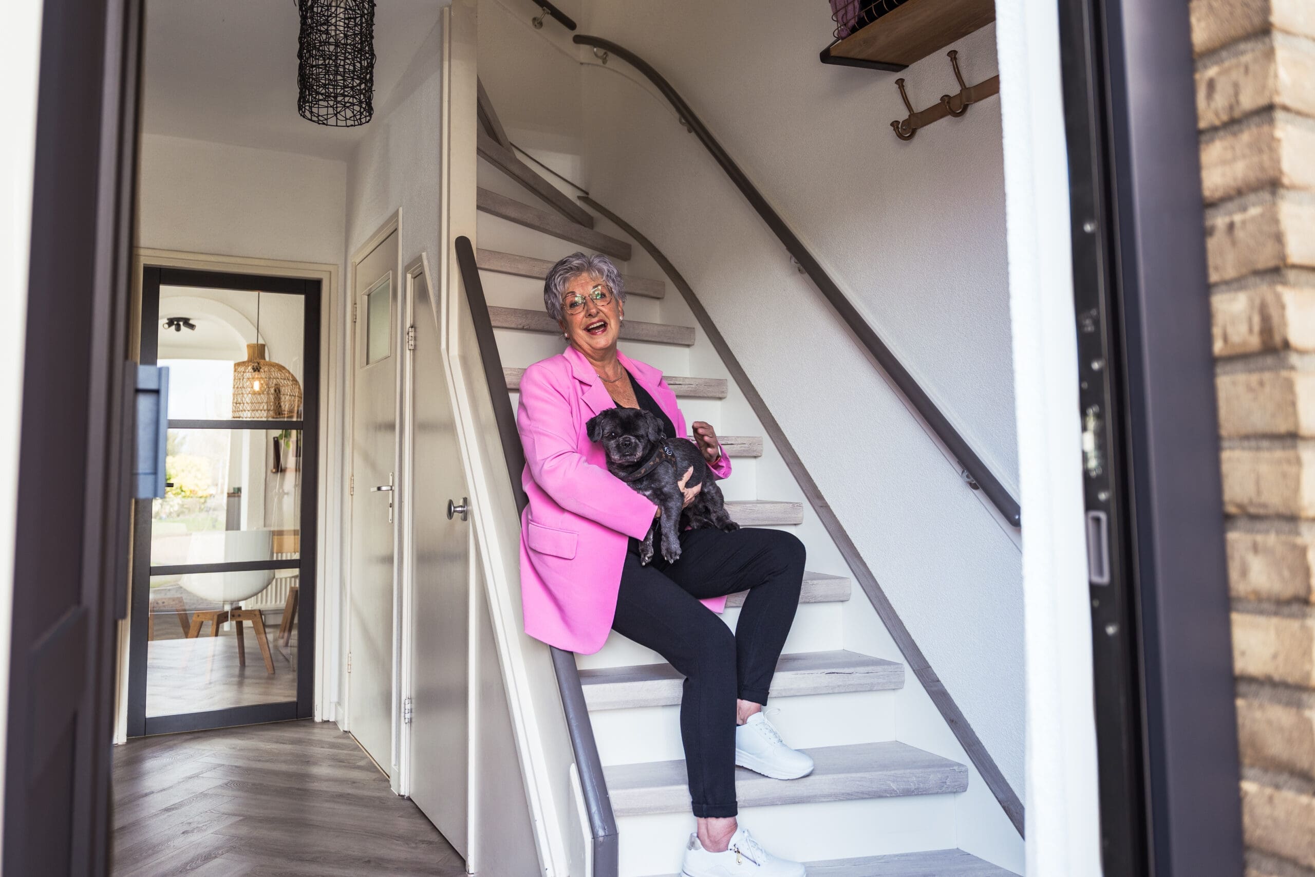 Vrouw zit samen met haar hondje op de pas gerenoveerde trap te lachen.